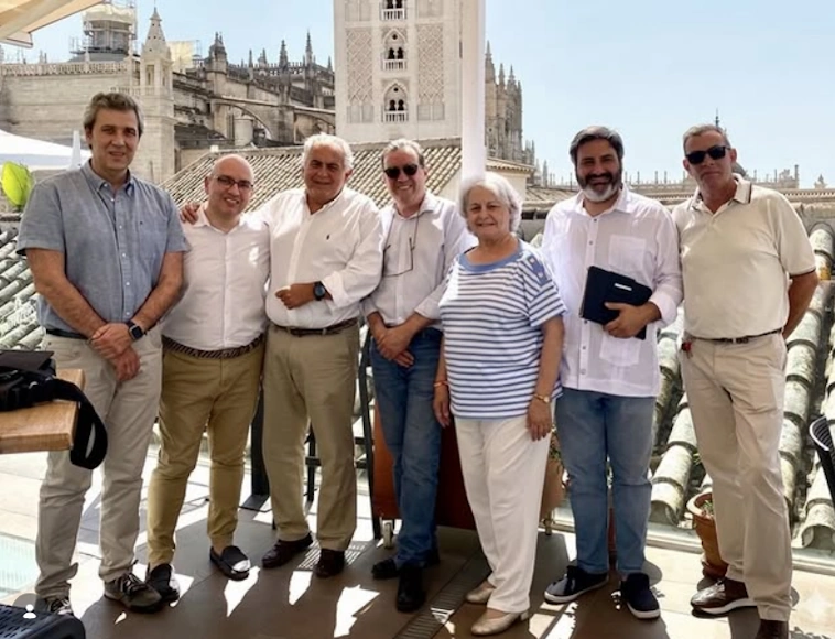 Manuel Domínguez junto a profesionales del turismo en una terraza de Sevilla con la Catedral y la Giralda al fondo