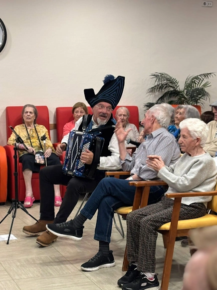 Músico con sombrero tradicional tocando para ancianos en residencia.