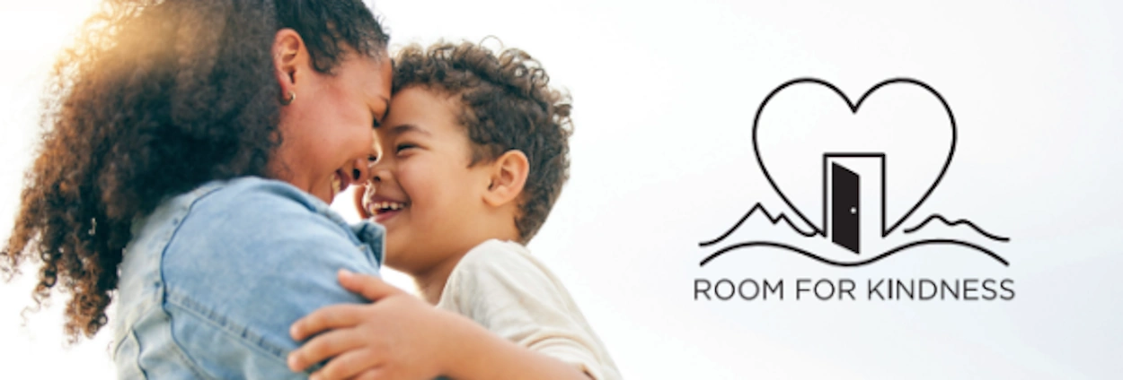 Una madre abraza a su hijo junto al logotipo de Room for Kindness