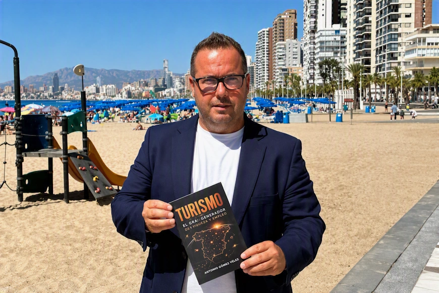 Agustín Almodóbar en la playa de Benidorm con su libro sobre turismo